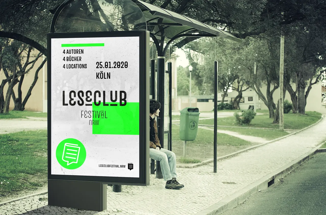 Person sitzt an einer Bushaltestelle in einem Park neben einem großen Plakat für das Lesesclub Festival.